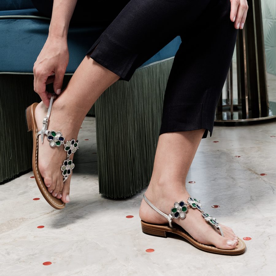 A woman fastening a jewelled sandal with a low heel