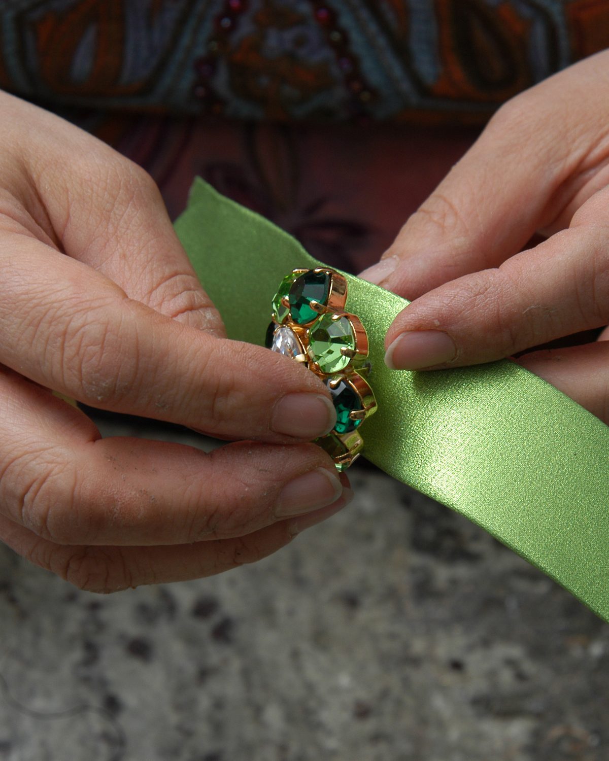 An artisan's hands fixing a jewelled ornament onto a strap